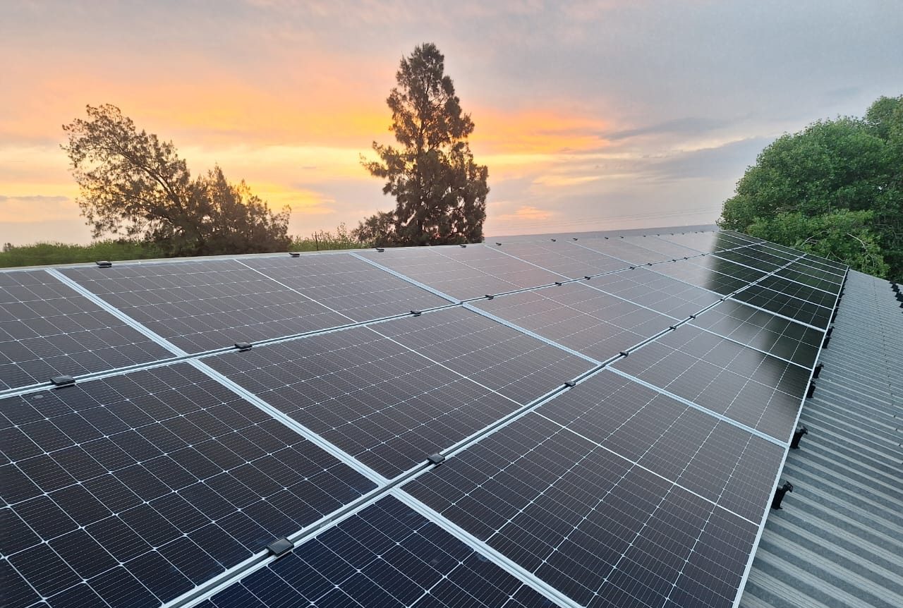 Solceller på ett tag vid solnedgång.