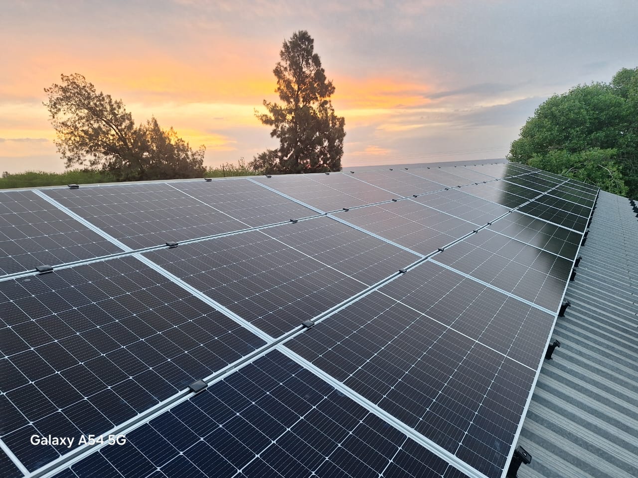 Solceller på ett tag vid solnedgång.